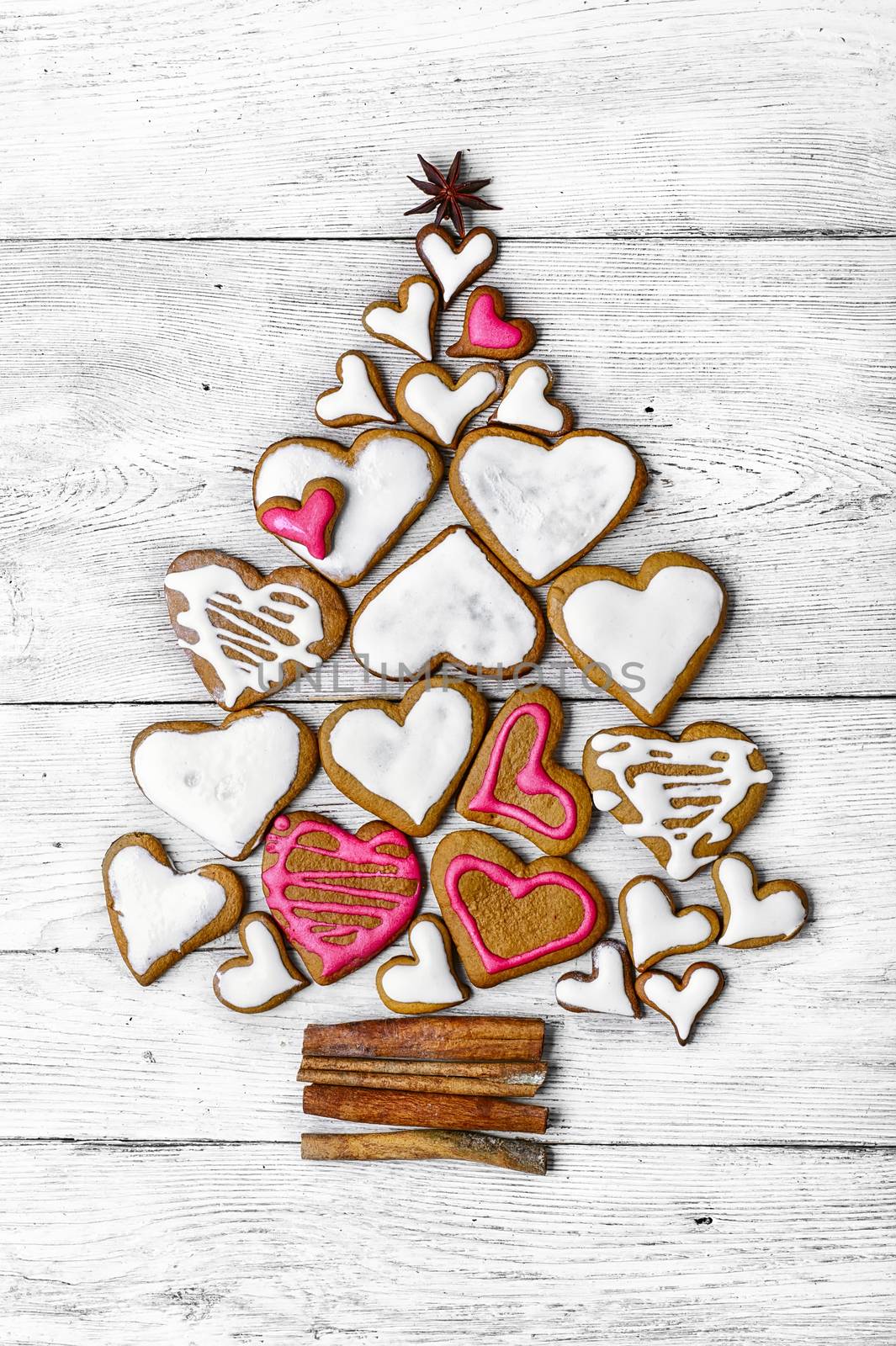 Christmas cookies are laid out in the shape of Christmas tree on light wooden background