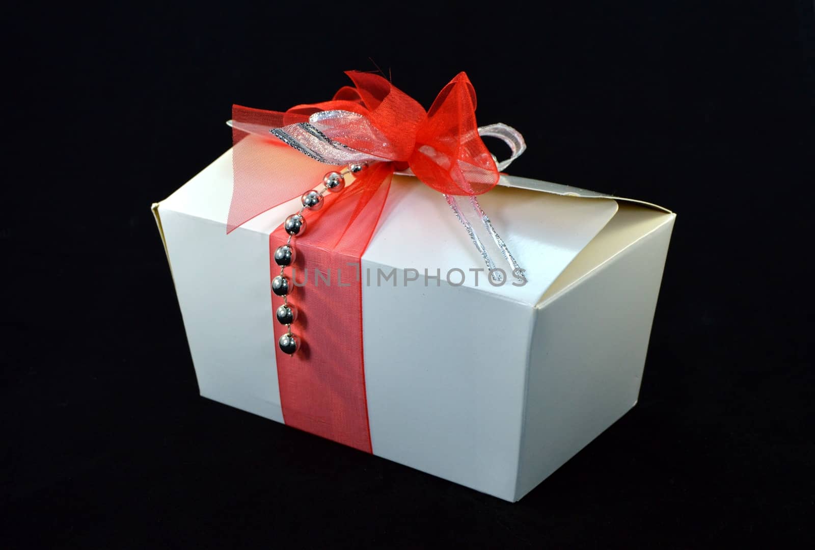 Box of white pralines with a bow on a black background