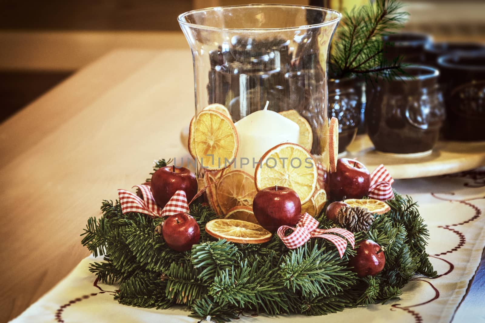Candle in a glass vase and Christmas decoration on a wooden table