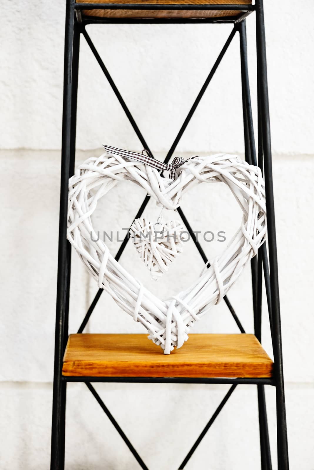 Heart within a heart decorative prop standing on metal and wooden stand against the white wall