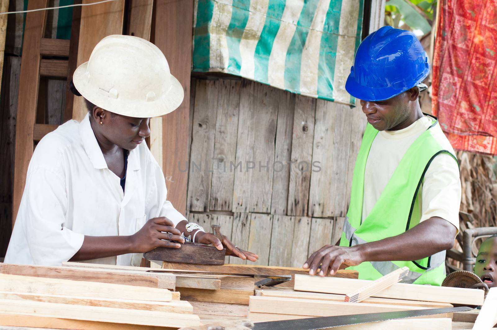 Young woman learning carpentry with her teacher in front of  her.