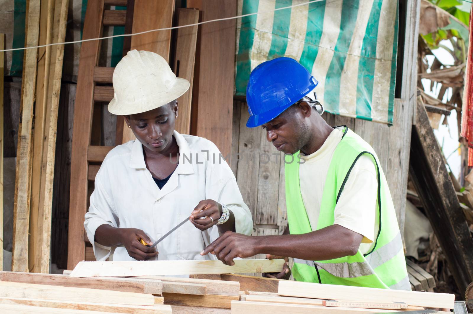 The teacher explains to his trainee how to take measurements of the wood.