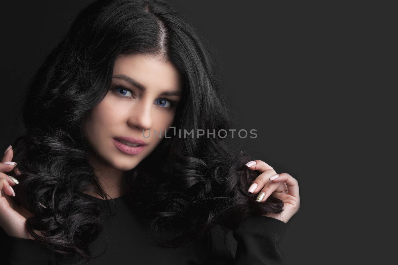 Beautiful woman holding her dark curly hair