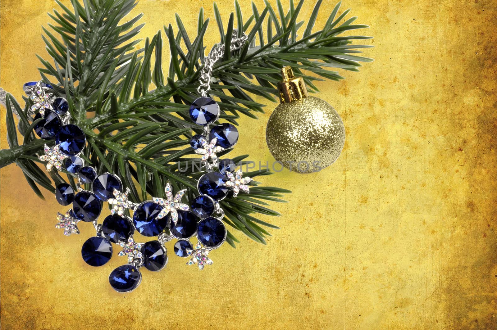 necklace with blue stones on a branch of a Christmas tree with a  ball on an abstract background