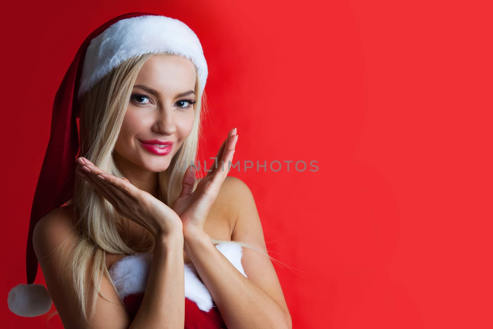 Portrait of beautiful smiling woman in santa hat on red background