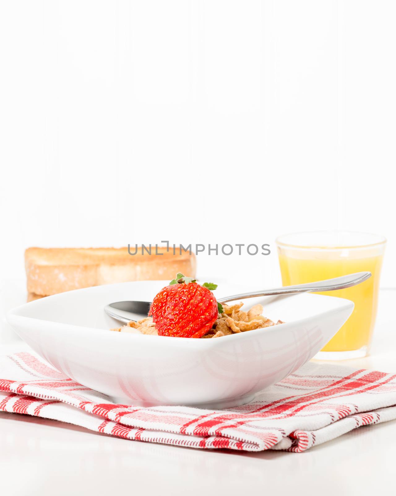 Bowl of breakfast cereal served with toast and orange juice.