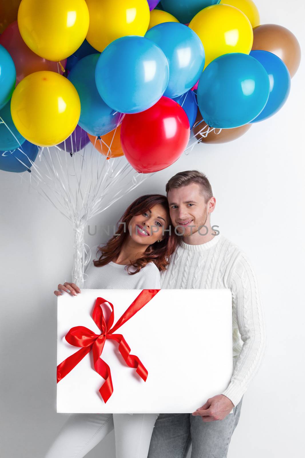 Young smiling couple with balloons and big gift box