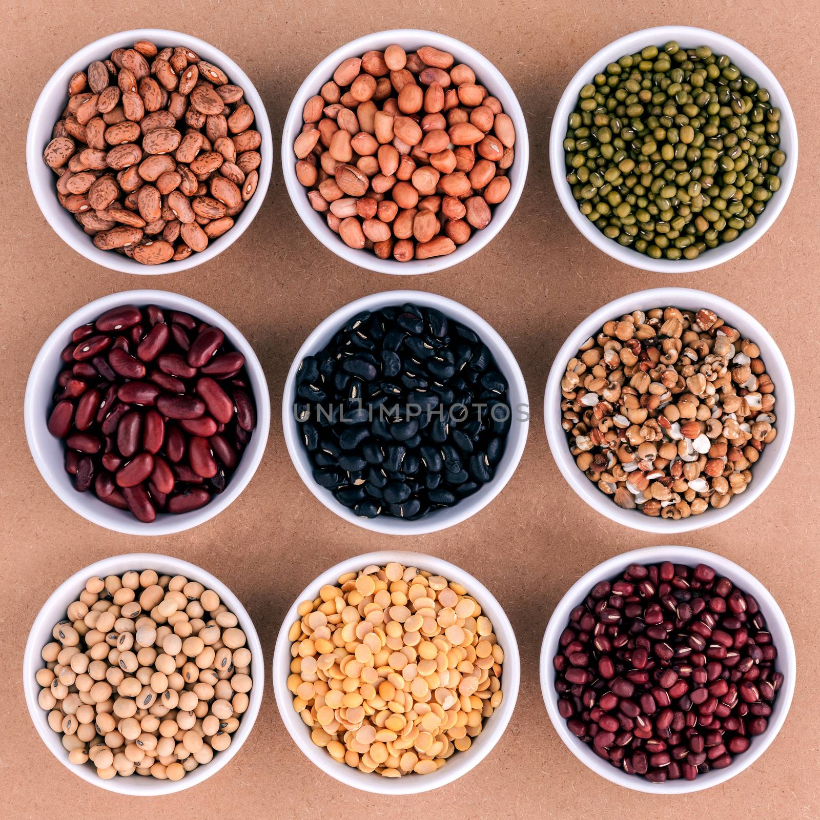 Mixed beans and lentils in the white bowl  on brown background. mung bean, groundnut, soybean, red kidney bean , black bean ,red bean,green bean,millet and brown pinto beans .