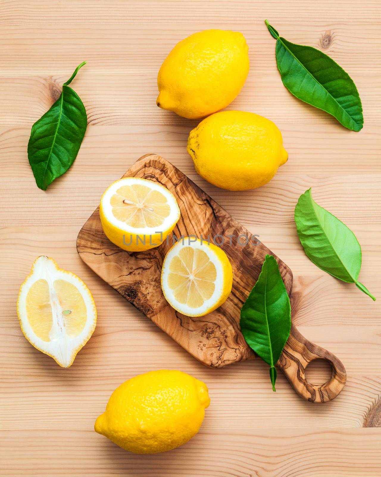 Fresh lemons and  lemons leaves on rustic wooden background. Fresh lemons and lemon slice on wooden table with flat lay.  Fresh citrus fruit background.