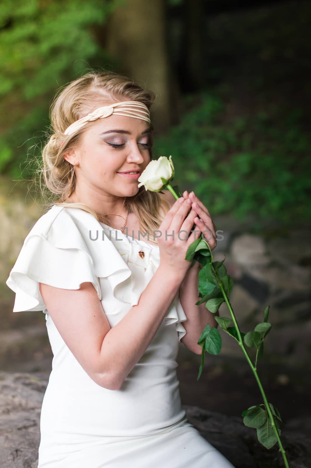 beautiful girl sniffing white rose in the Park