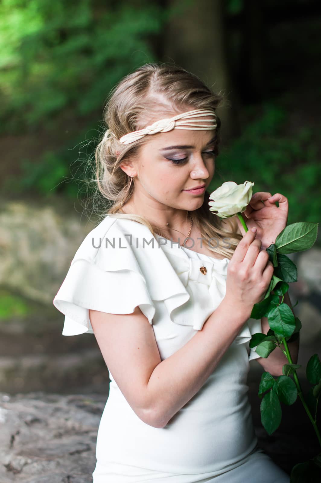 beautiful girl sniffing white rose in the Park