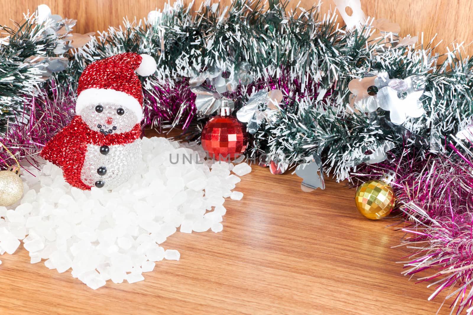 Snow Man on a pile of white crystalline with white background. Red and yellow Christmas Balls Ornaments on wood,