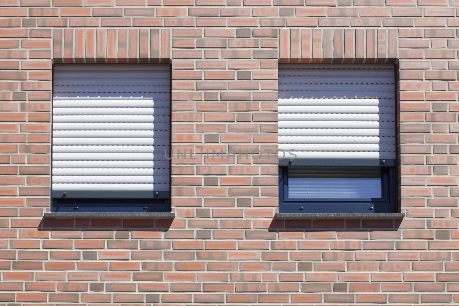 Windows with closed shutters on a red House Wall