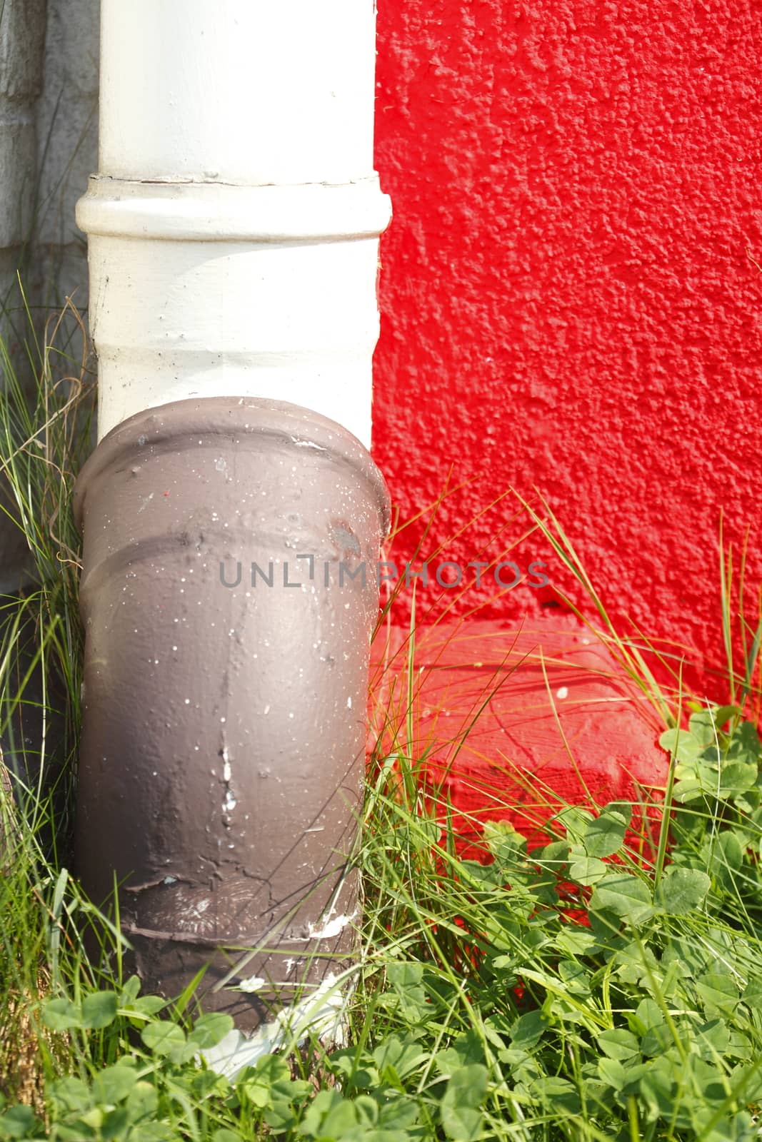  red painted  concrete house wall  with water pipe