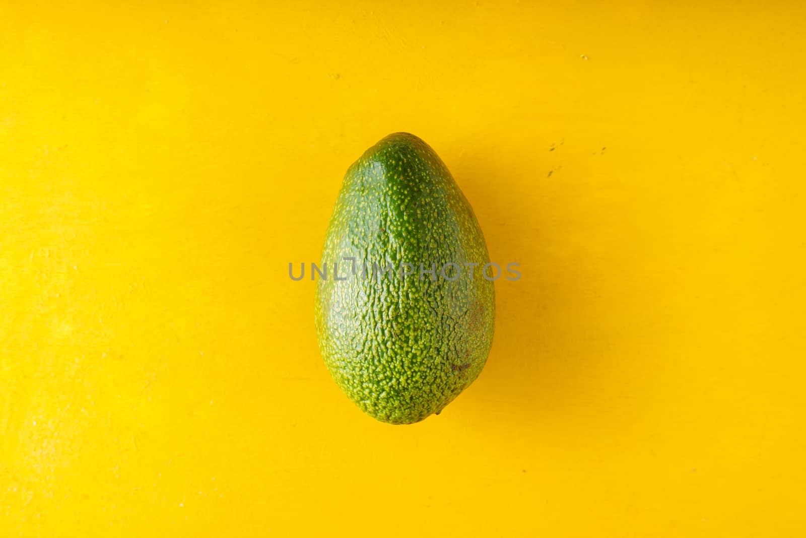 Avocado on a yellow table by Deniskarpenkov