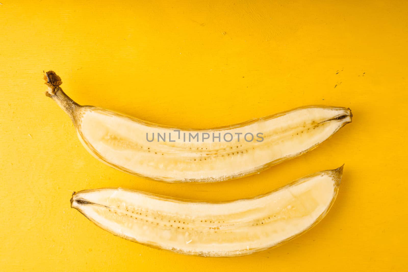 Halved yellow banana on the table by Deniskarpenkov