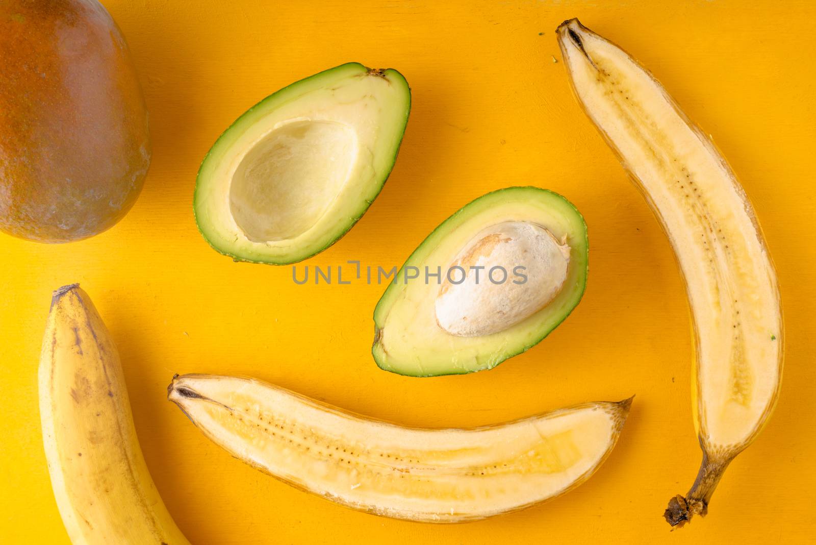Bananas and avocados on a yellow background horizontal