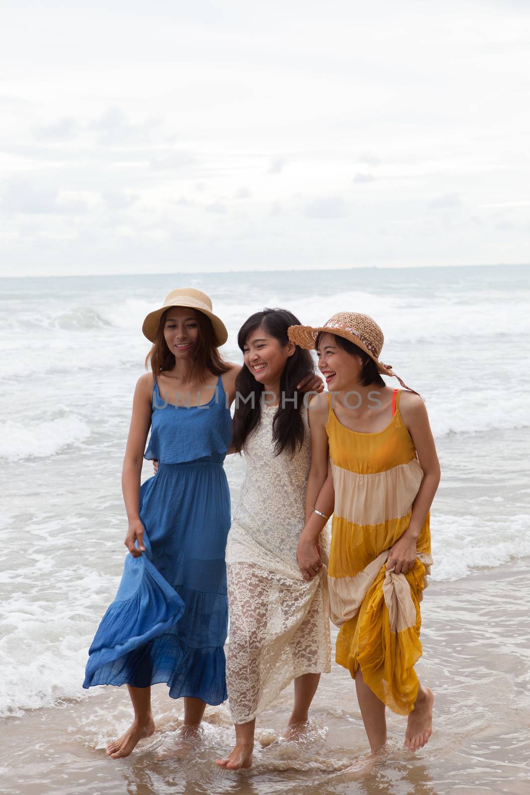 portrait of young asian woman with happiness emotion wearing beautiful dress walking on sea beach and laughing joyful use for people relaxing vacation on destination