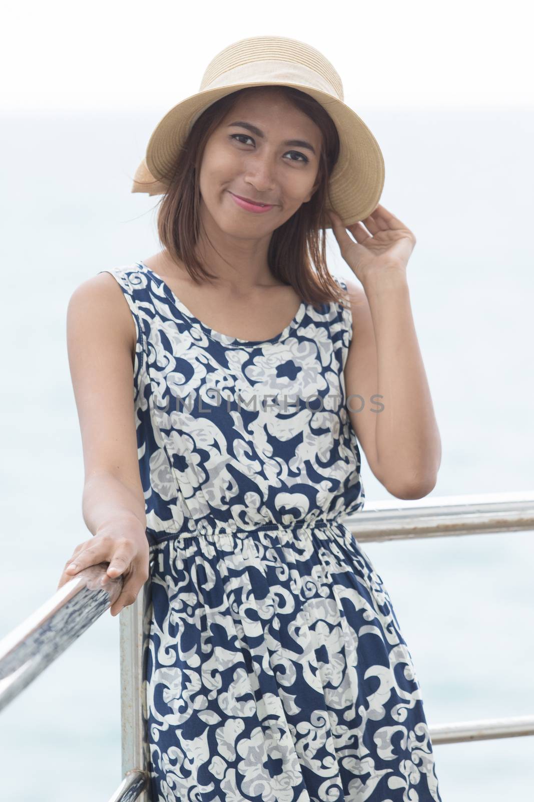 portrait of young beautiful asian woman wearting fashion straw hat standing on sea location
