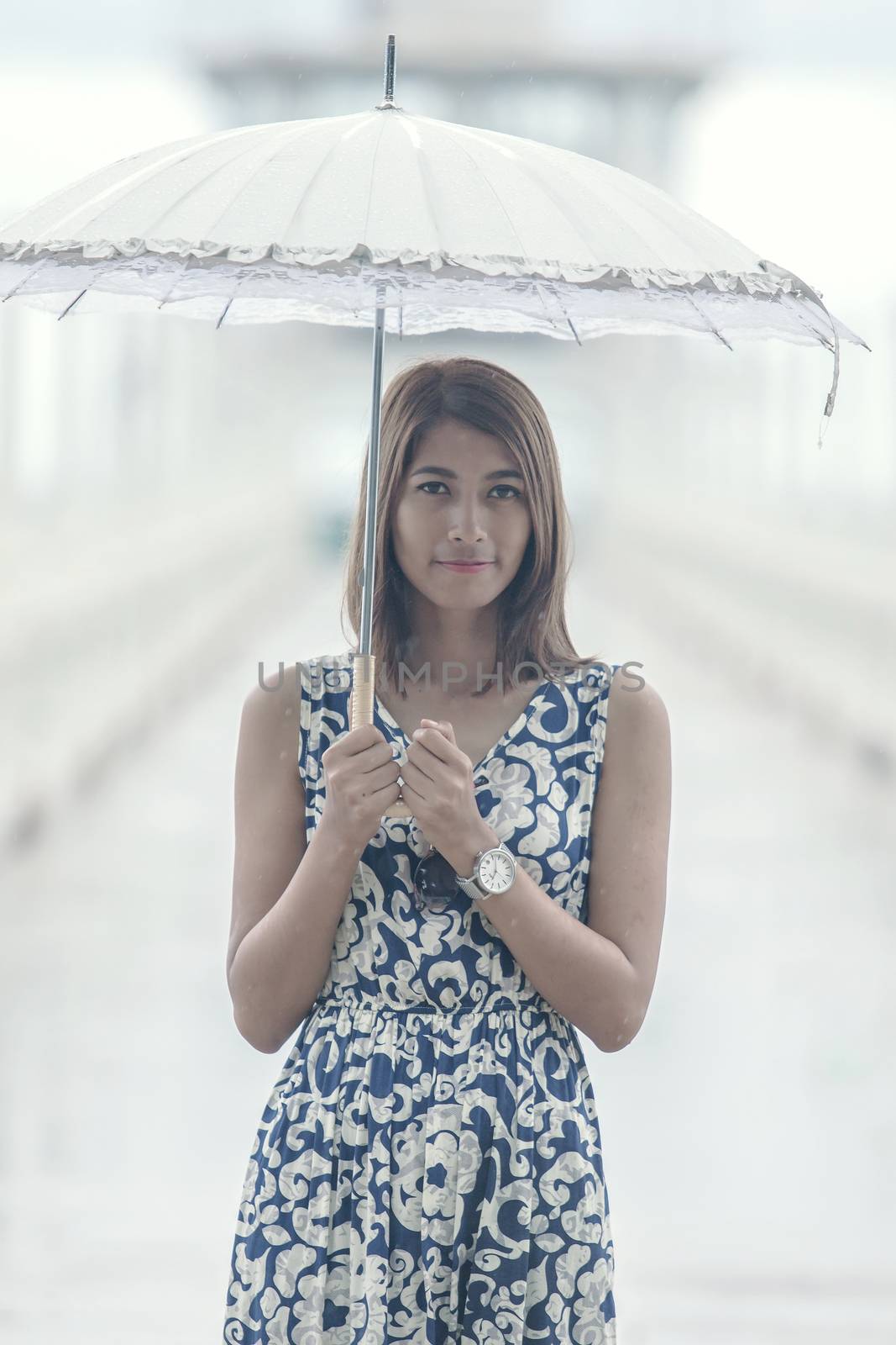 portrait of beautiful tan skin woman with umbrella standing among raining day 