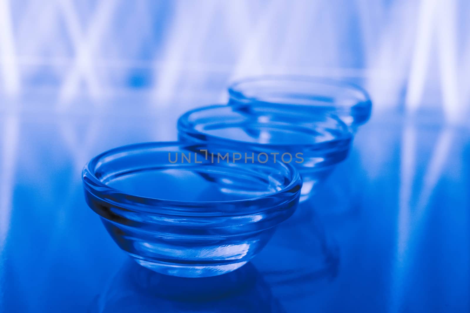 Three glass bowls on a blue background using light painting technique