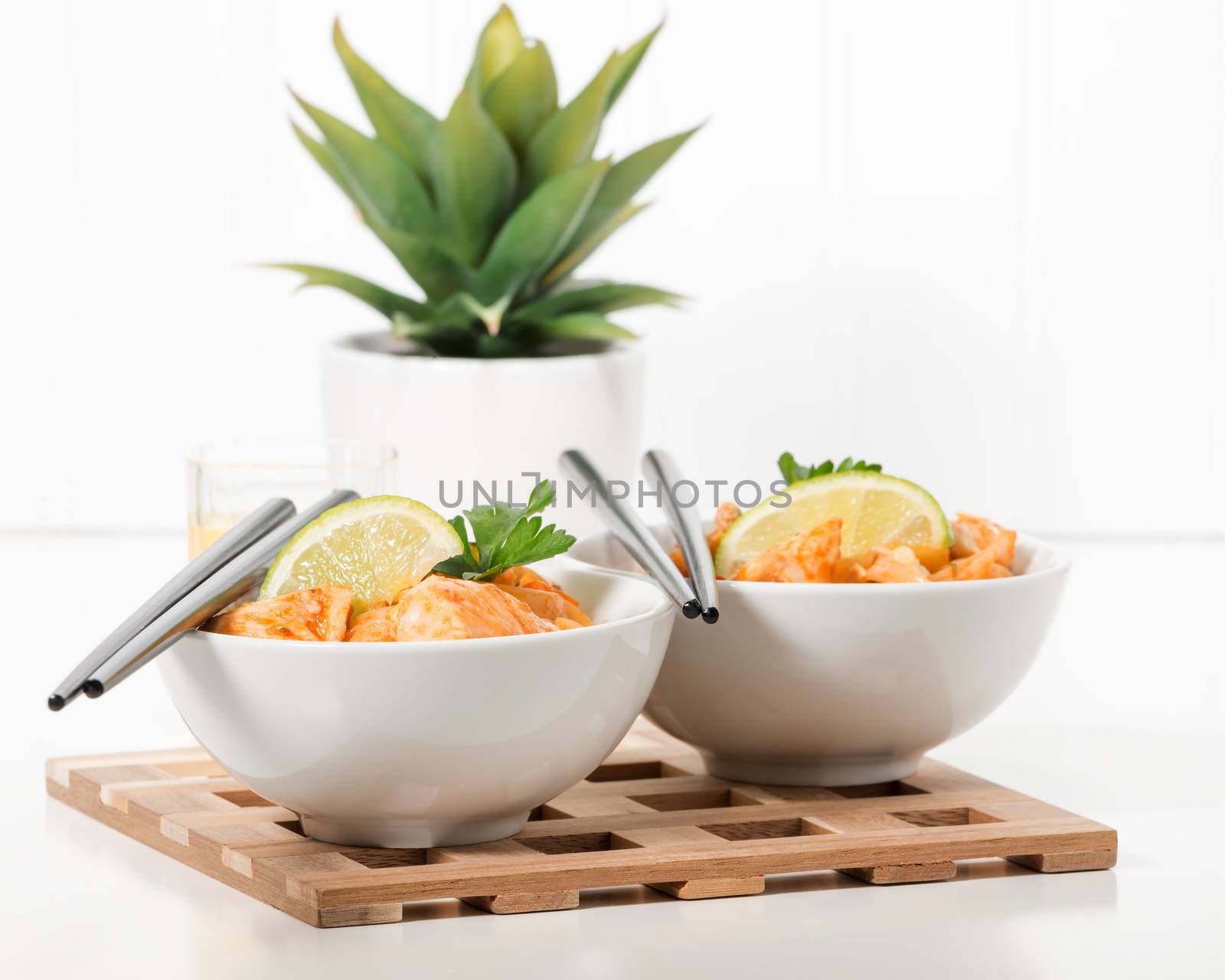 Two bowls of chicken pad thai garnished with lime.
