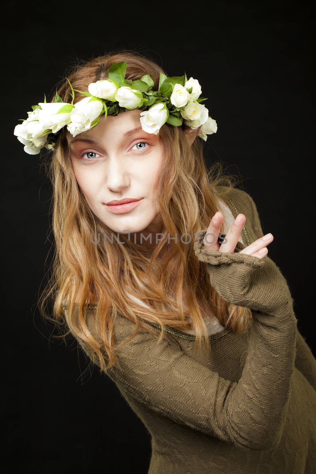 A smiling beautiful woman with white roses wreath in her long hair is holding or peeking behind nothing.