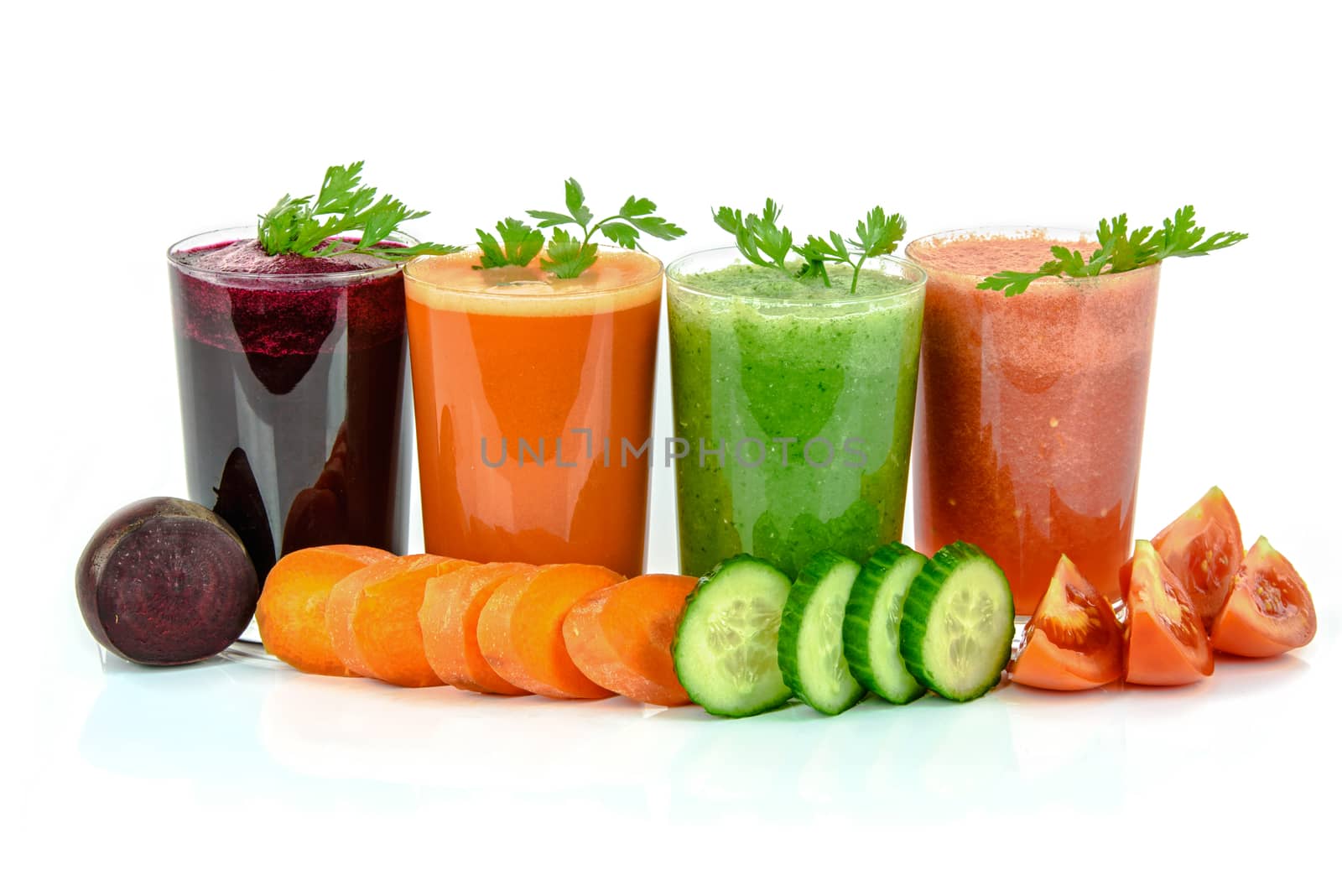 Four vegetable juices in glasses with parsley and vegetables isolated on a white background