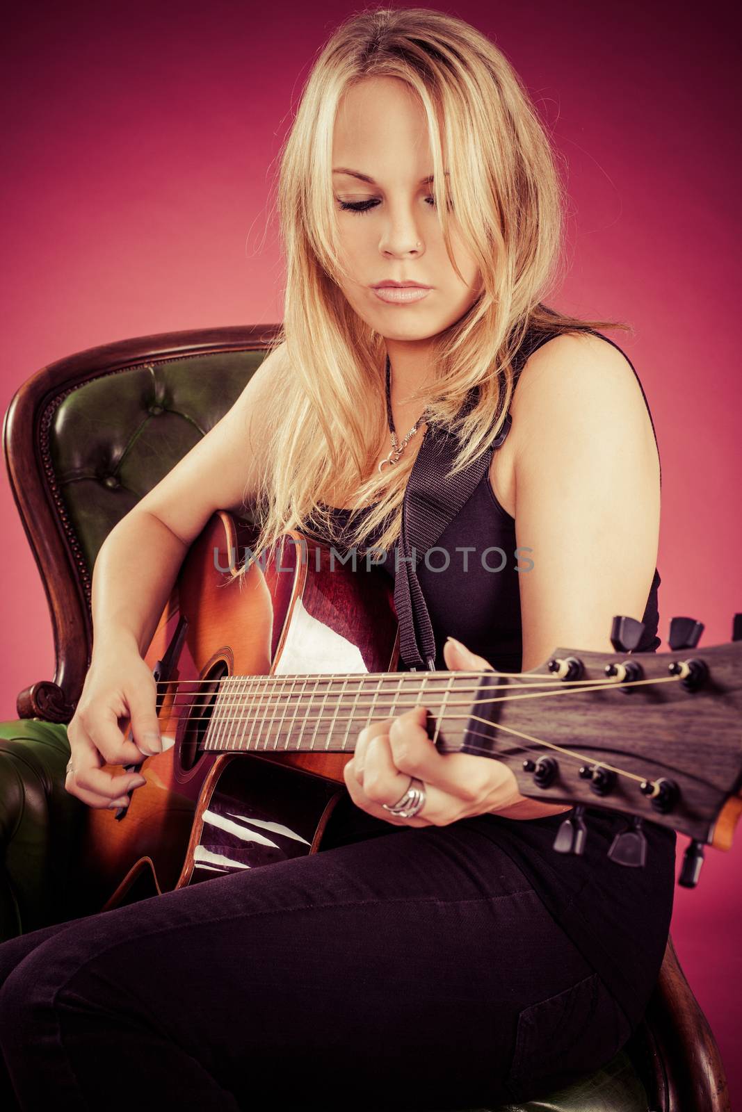 Photo of a beautiful blond female playing an acoustic guitar.