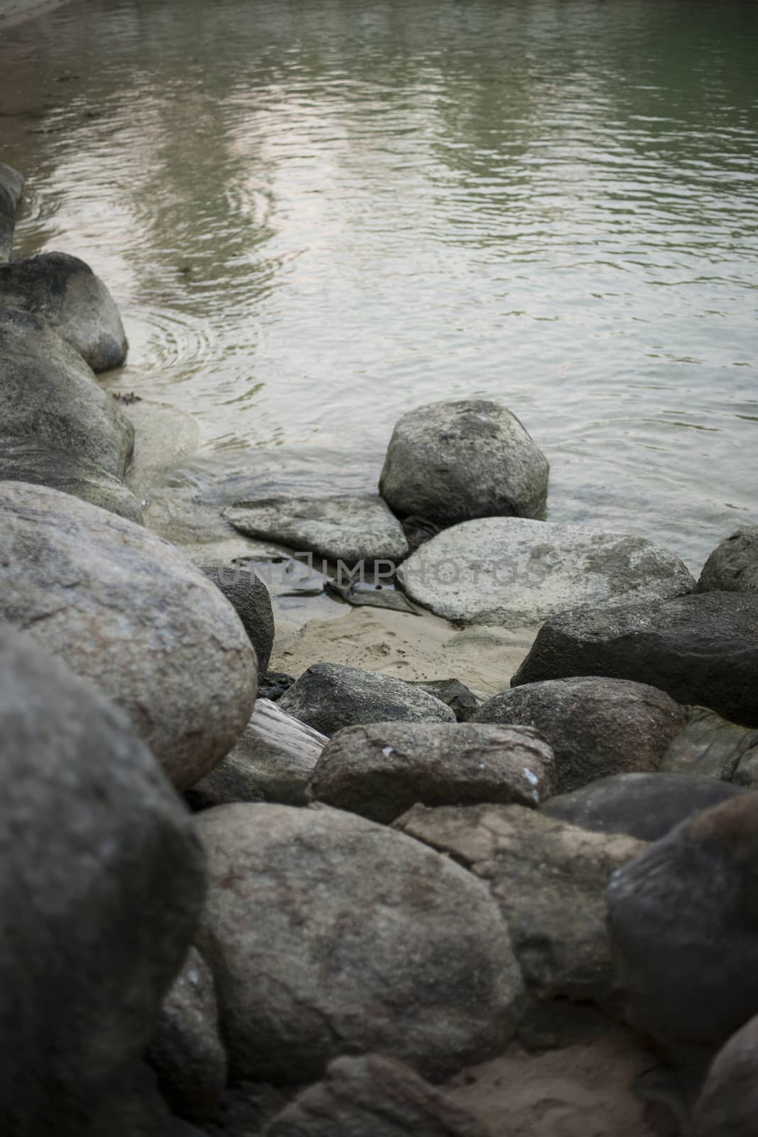 The river flows around stones on the shore