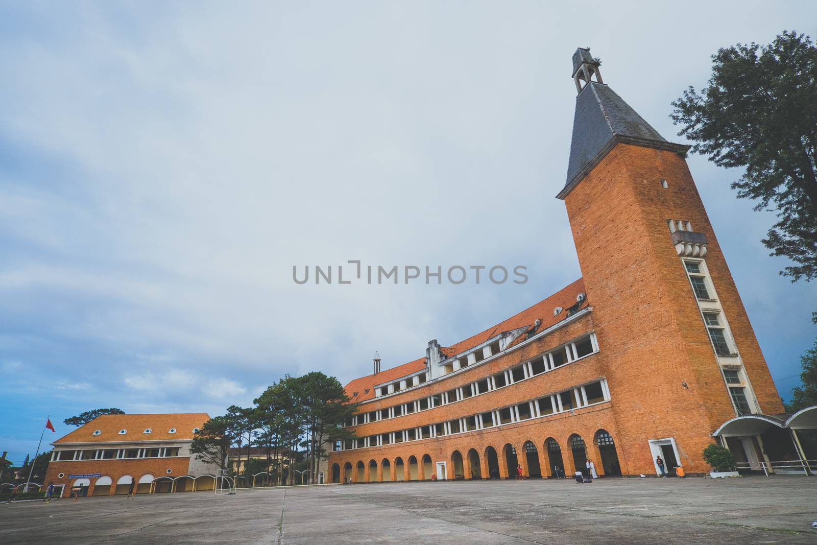 Arched architectural beauty, rustic buildings Pedagogical University in sunny with red roofing tiles impressive pines in Da Lat city, Lam Dong, Vietnam