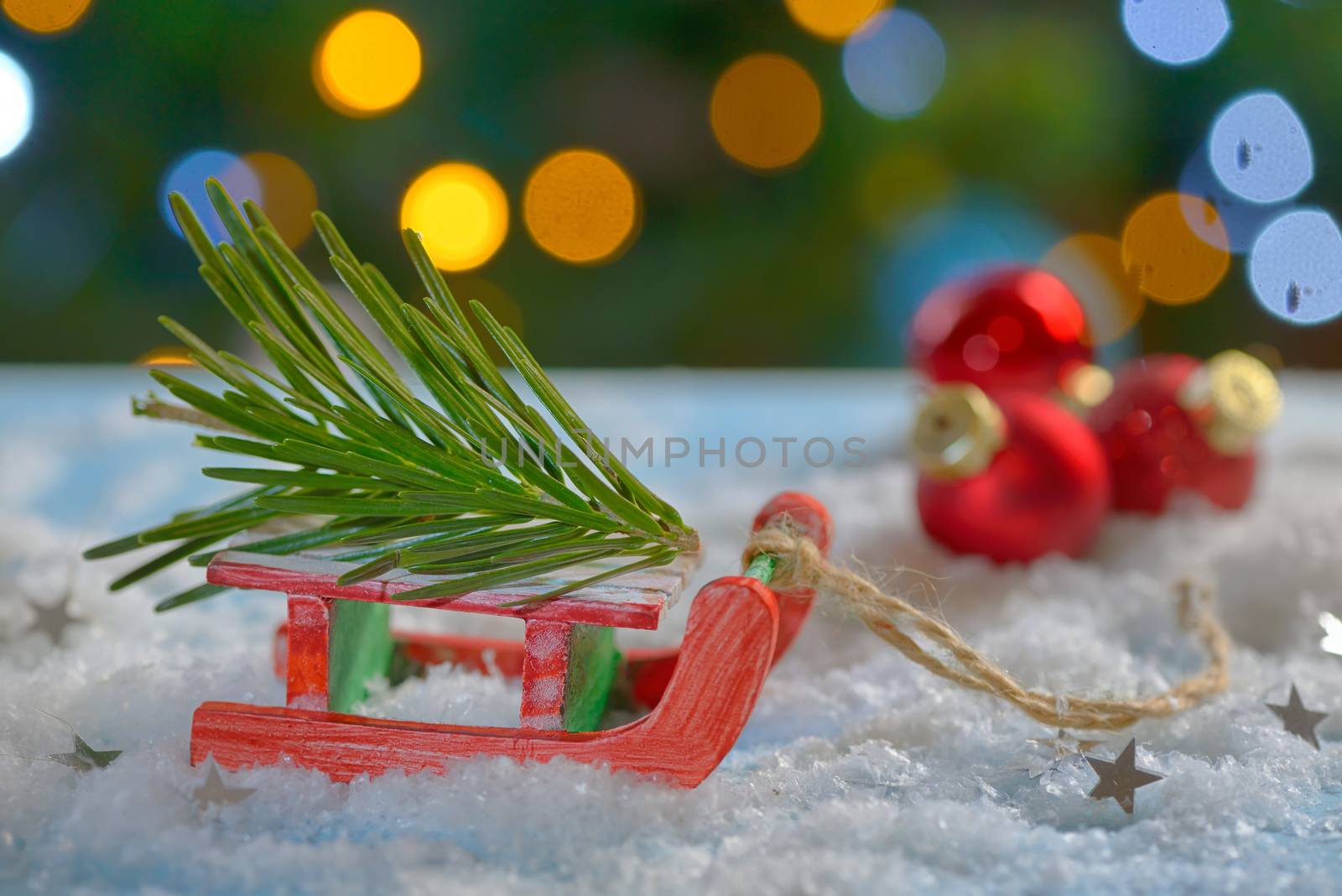 Red sleigh toy and Christmas tree on fake snow