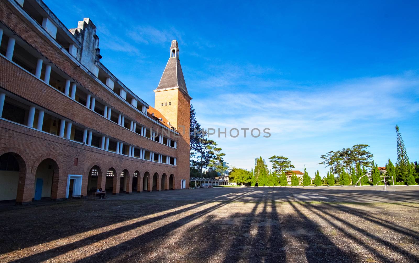 Arched architectural beauty, rustic buildings Pedagogical University in sunny with red roofing tiles impressive pines in Da Lat city, Lam Dong, Vietnam