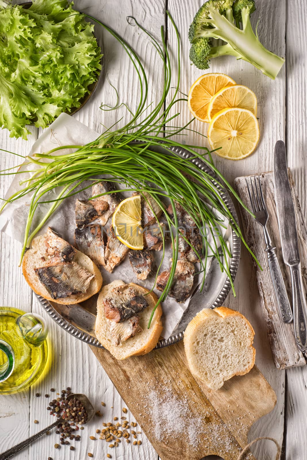 Fresh greens, sardines, bread on a wooden table by Deniskarpenkov