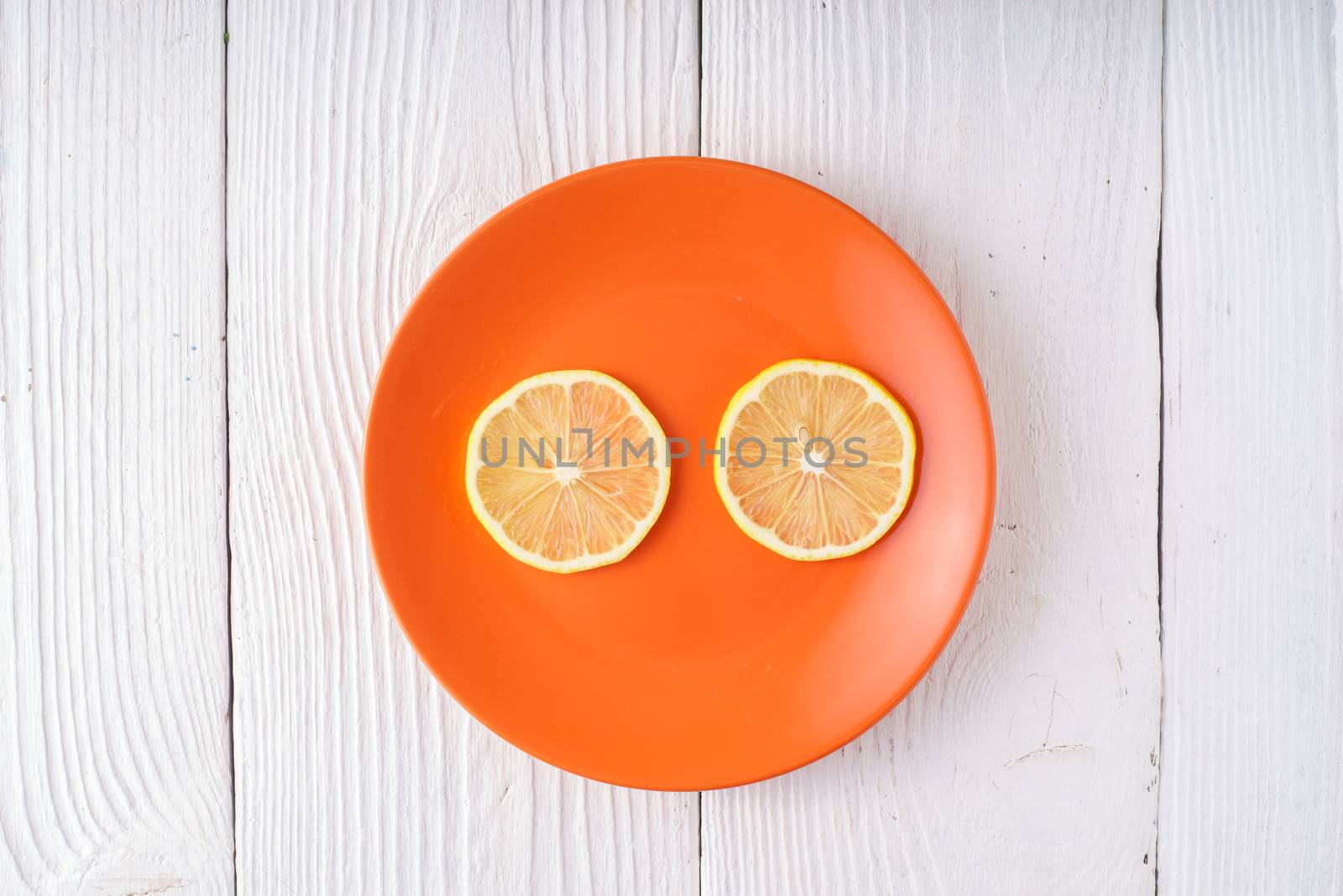 Round slices of lemon on orange plate by Deniskarpenkov