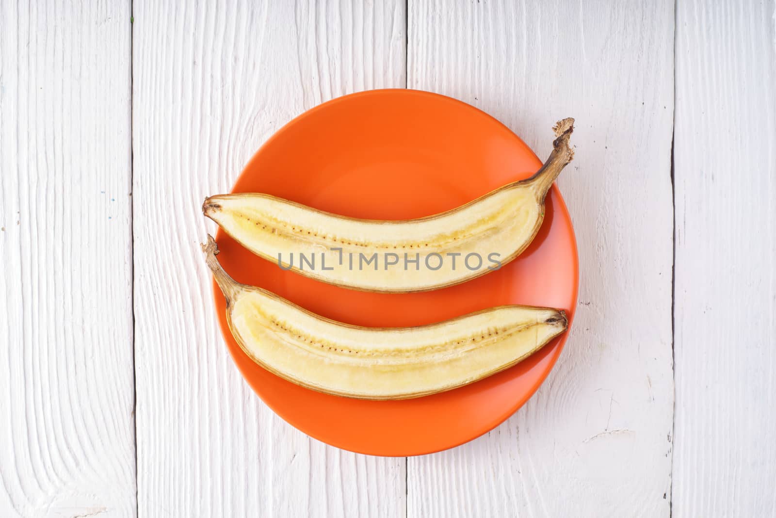 Banana halves lie on orange plate horizontal