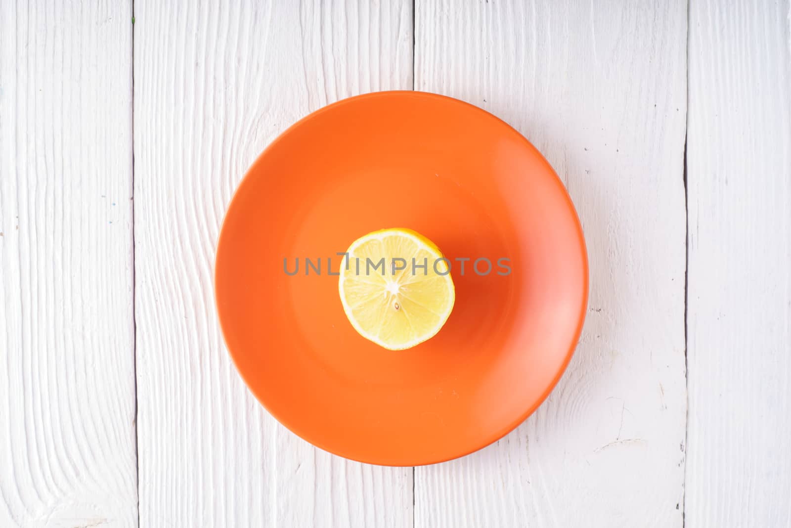 Half of lemon on orange plate horizontal