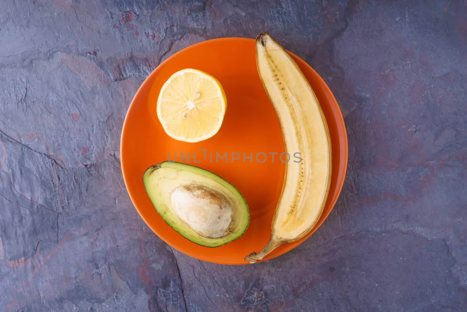 Tropical fruits on orange plate by Deniskarpenkov