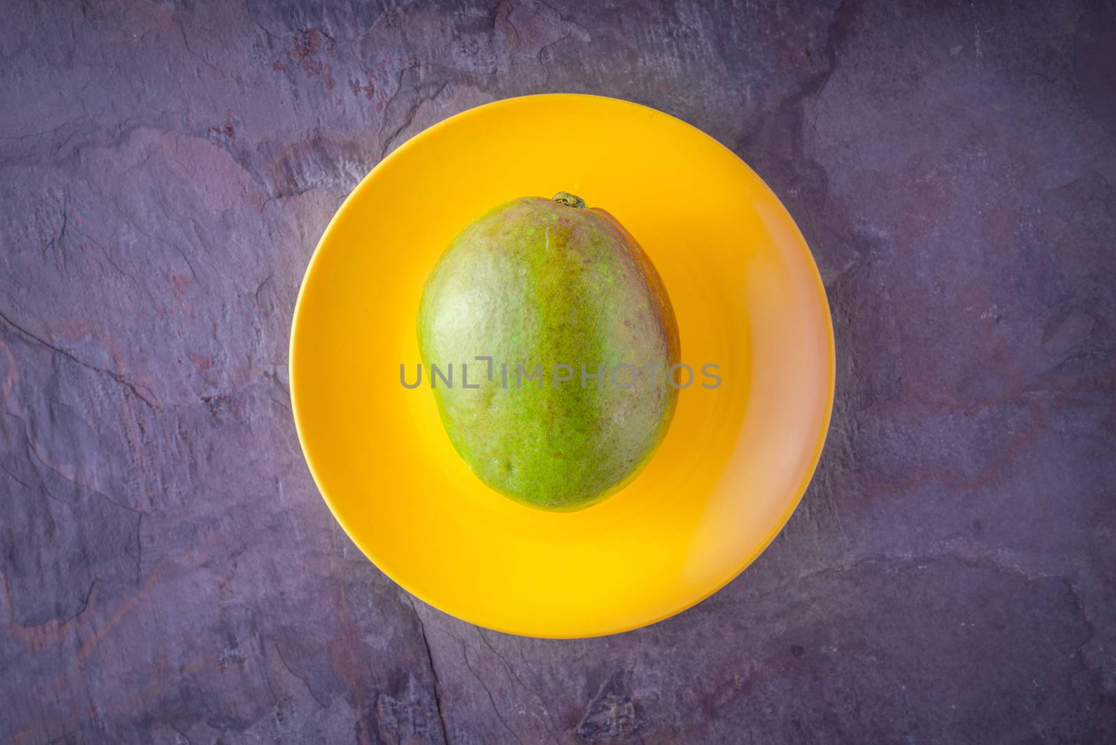 Mango lying on a yellow plate horizontal