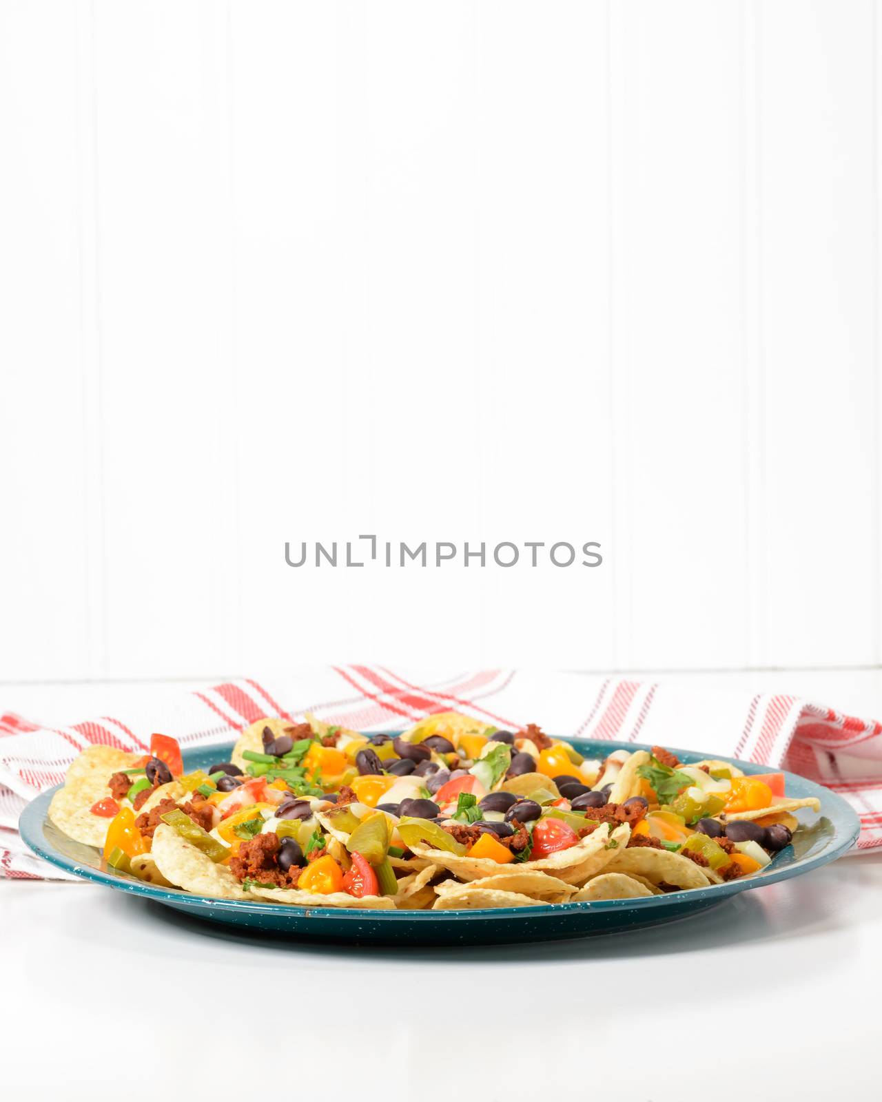Delicious hot nachos on a green tin platter.