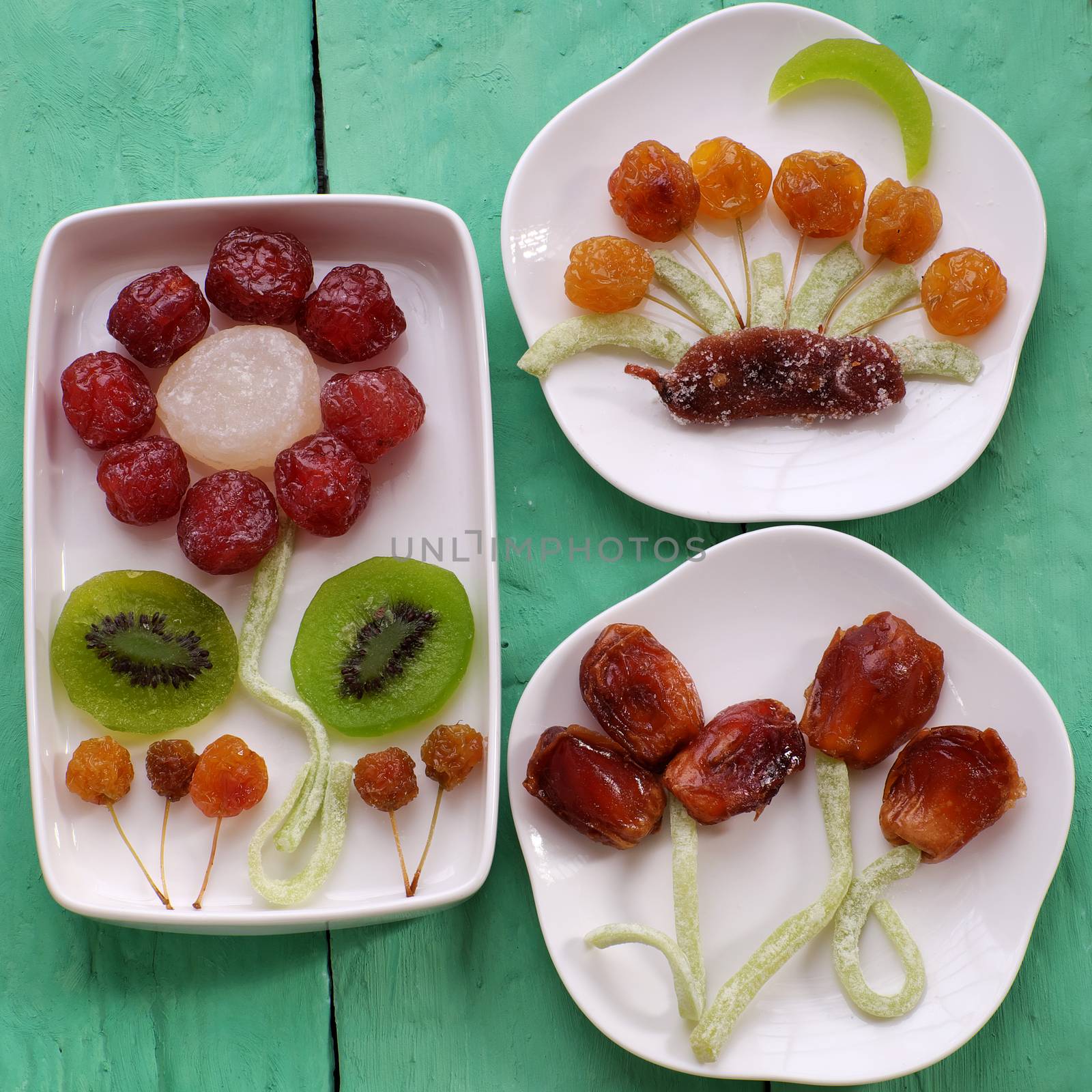 Vietnamese food for Vietnam Tet holiday, also lunar new year of Asia, colorful preserved fruit as kiwi, damson jam, or coconut jam set up on white plate with green wood background make art