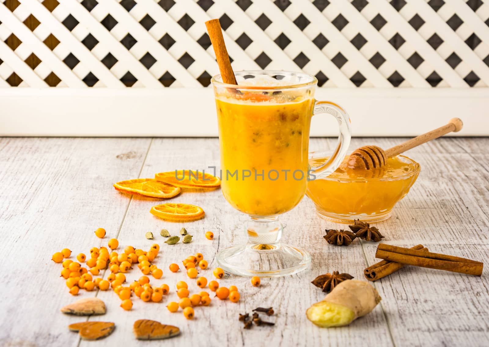sea buckthorn tea with honey, sea buckthorn , cinnamon, carnation and orange slices on a white wooden table