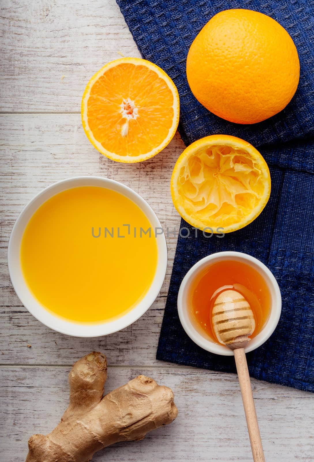 oranges, orange juice with honey and ginger lie on a white wooden table