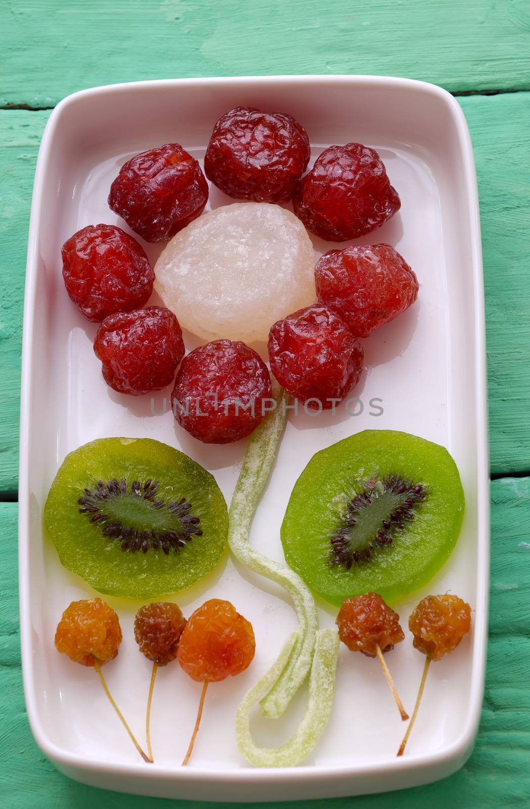 Vietnamese food for Vietnam Tet holiday, also lunar new year of Asia, colorful preserved fruit as kiwi, damson jam, or coconut jam set up on white plate with green wood background make art