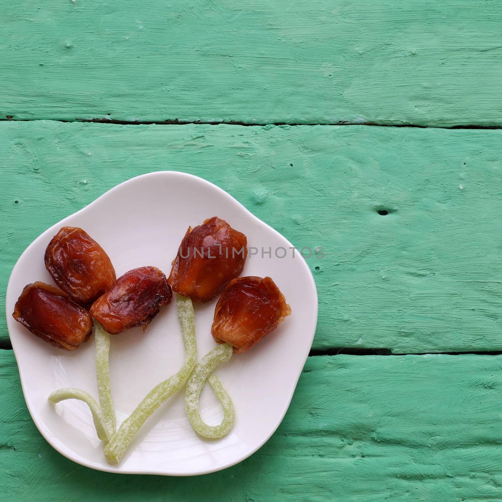 Vietnamese food for Vietnam Tet holiday, also lunar new year of Asia, colorful preserved fruit as kiwi, damson jam, or coconut jam set up on white plate with green wood background make art