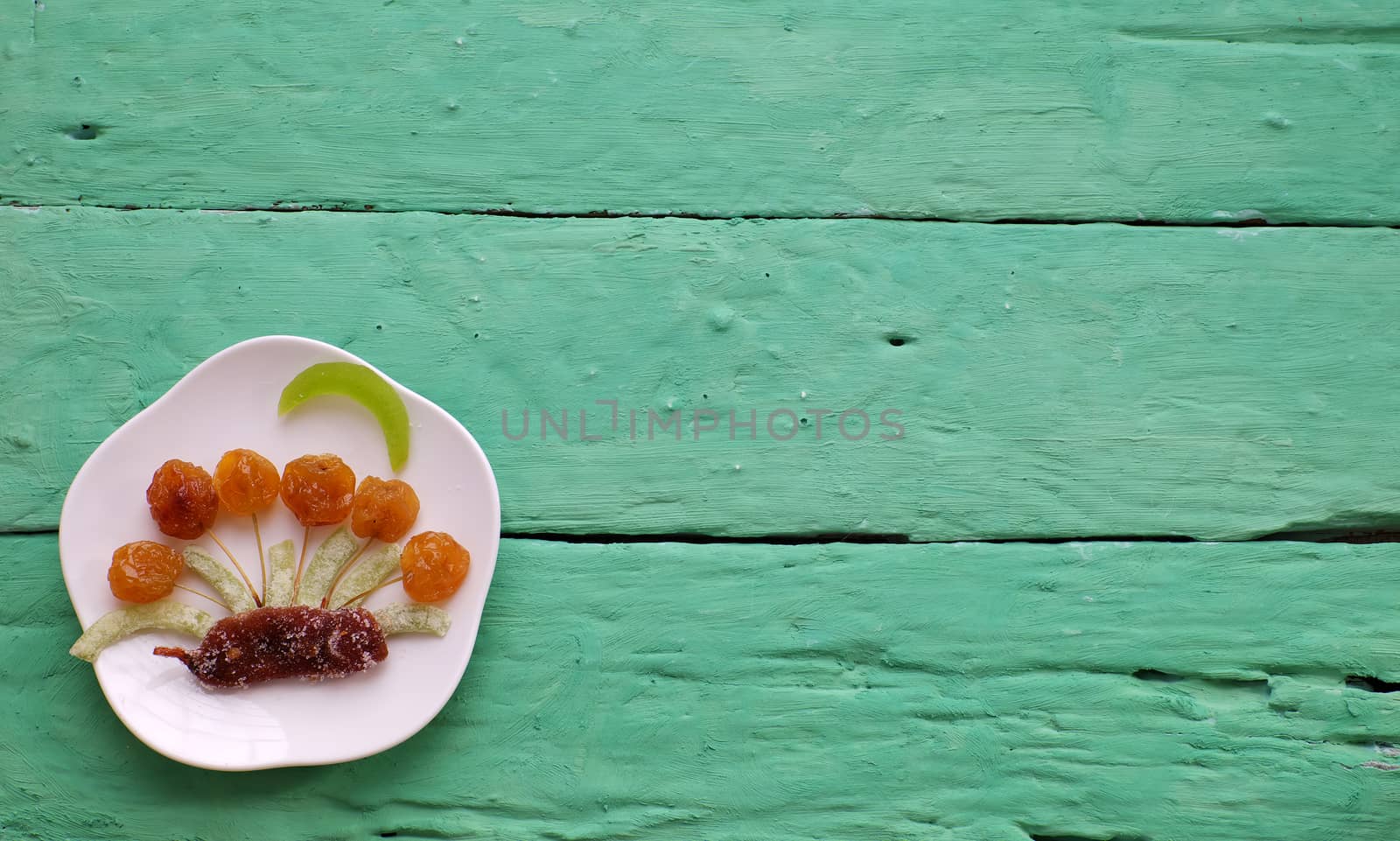 Vietnamese food for Vietnam Tet holiday, also lunar new year of Asia, colorful preserved fruit as kiwi, damson jam, or coconut jam set up on white plate with green wood background make art