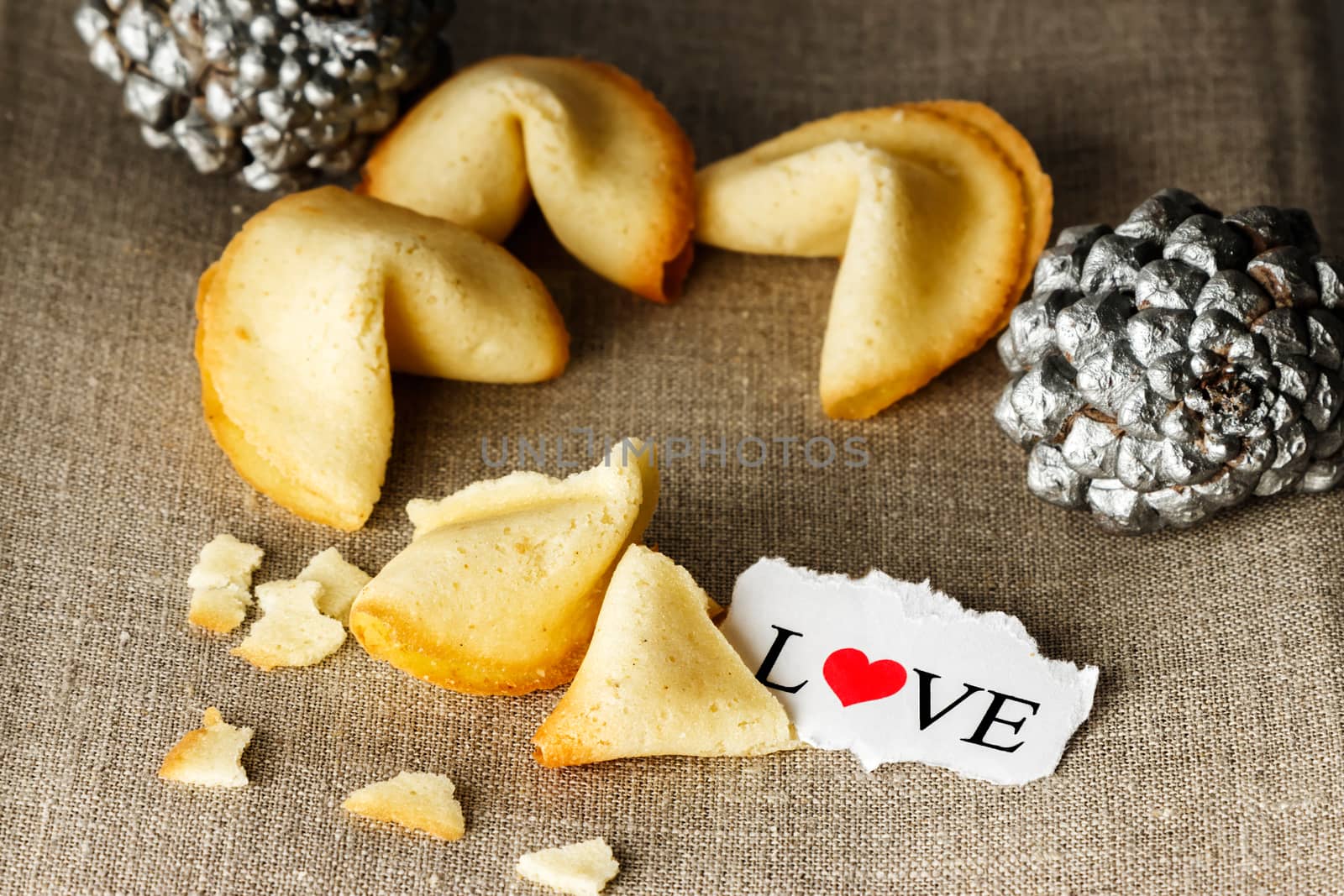 Cookies shaped like tortellini with the word love written on a paper and two silver pineapples in the background.Horizontal image.