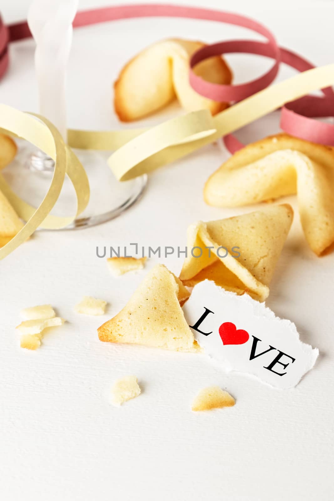 Cookies shaped like tortellini with the word love written on a paper and a glass of champagne with streamers.Vertical image.