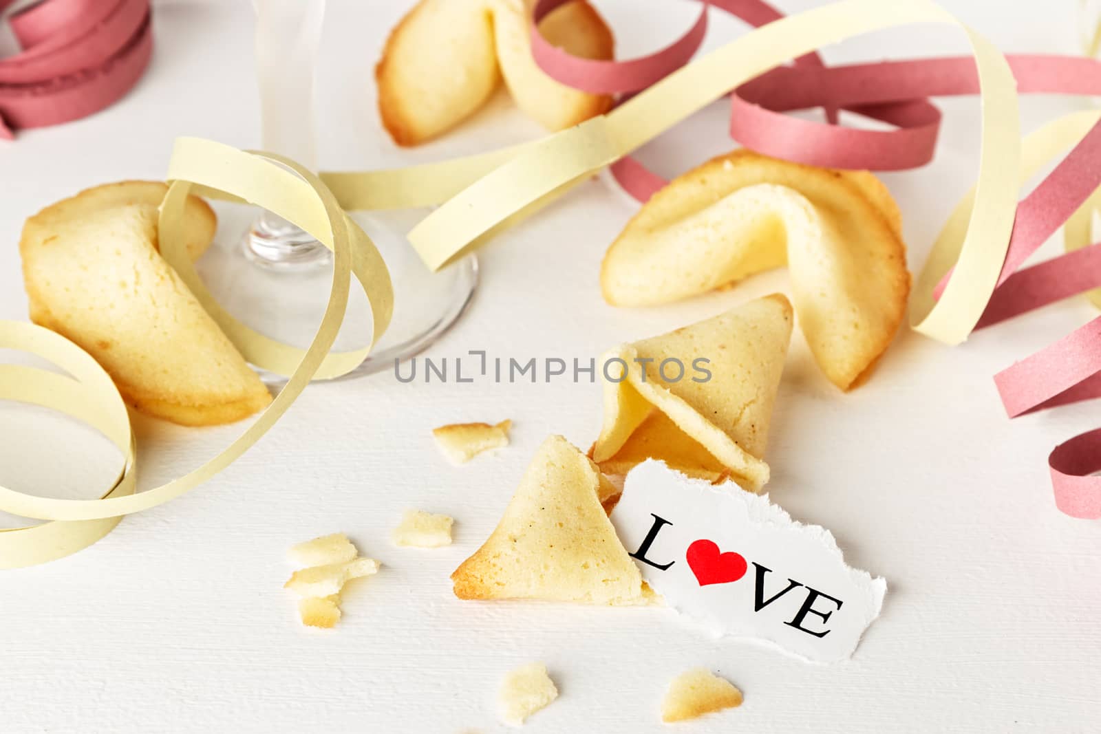 Cookies shaped like tortellini with the word love written on a paper and a glass of champagne with streamers.Horizontal image.