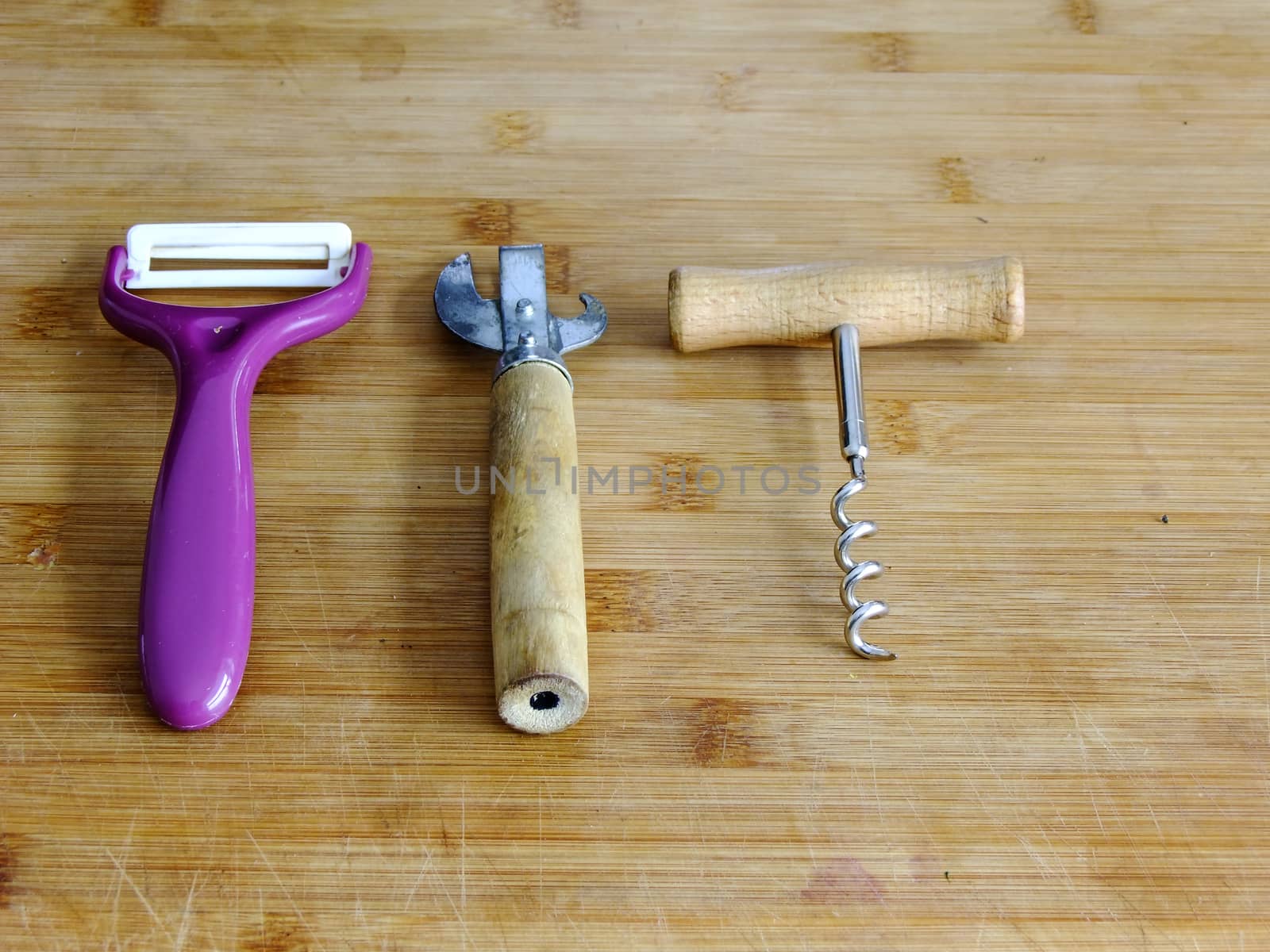 Potato Peeler, Can Opener and Bottle Opener on left Side of wooden Cutting Board
